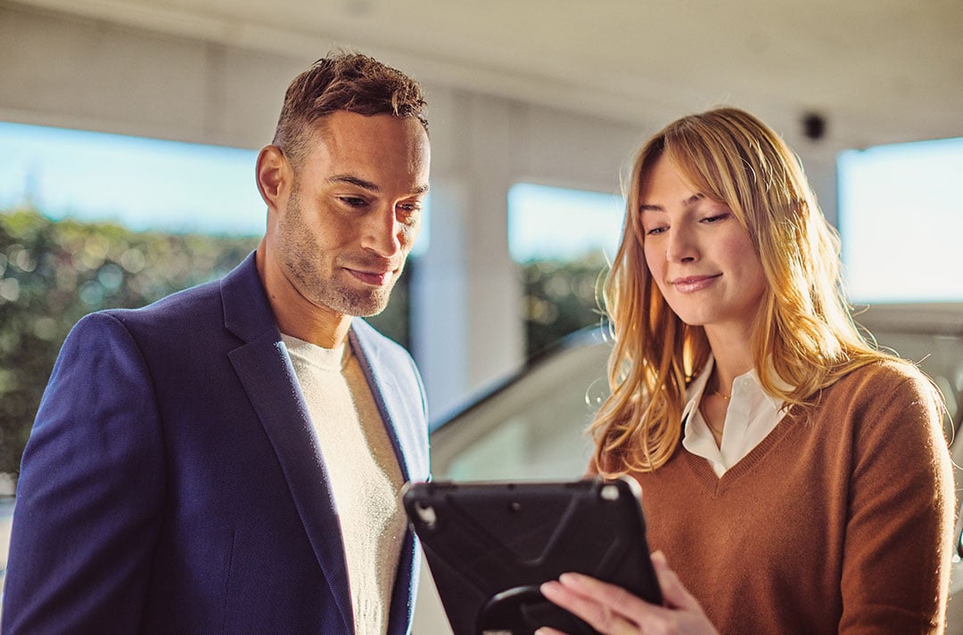 A female Lexus consultant consults with a corporate man on a tablet at a Lexus dealership