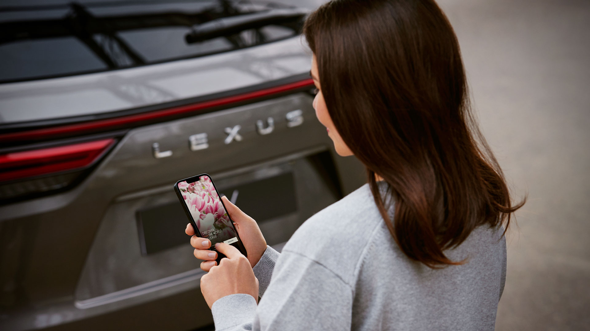 Woman holding phone with Lexus Encore app displayed