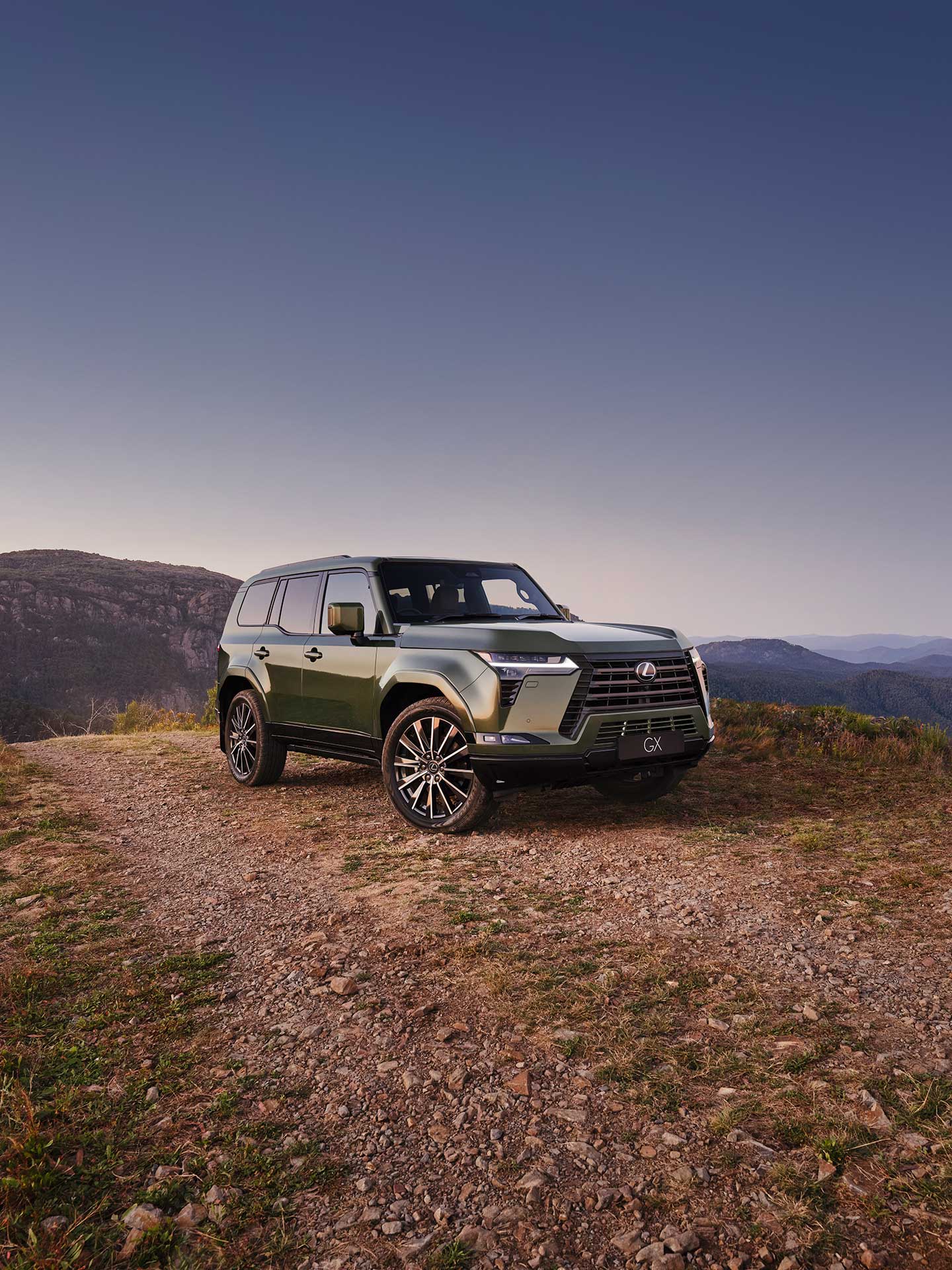 Pre-production GX Sports Luxury model shown parked on a clifftop. Blue, tree topped mountains are in the background.